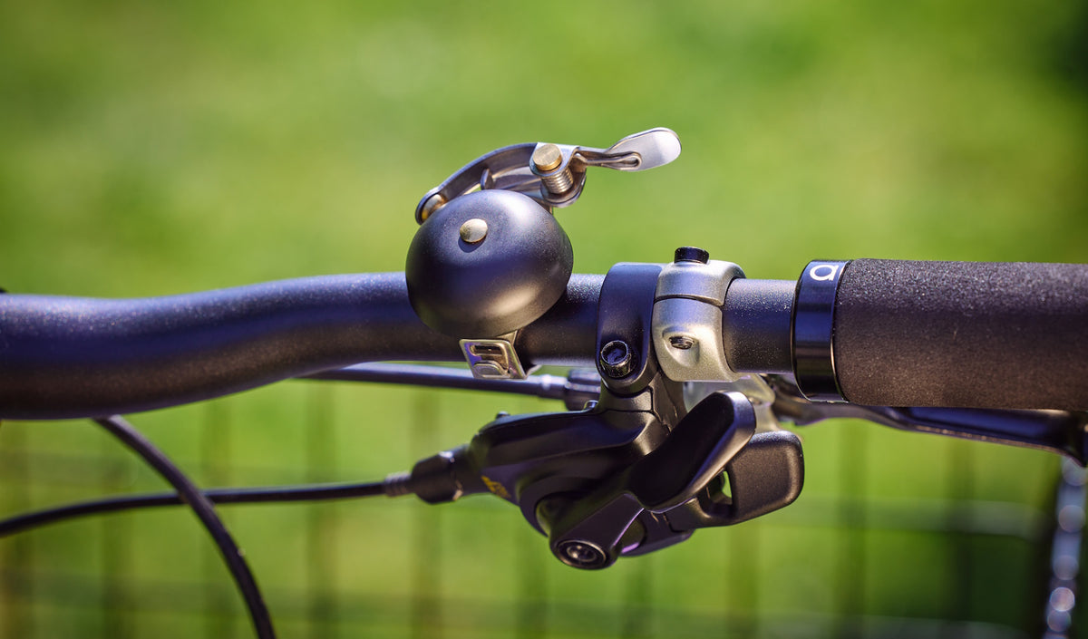 Satin black King of Ding 40mm bicycle bell on a black handlebar.