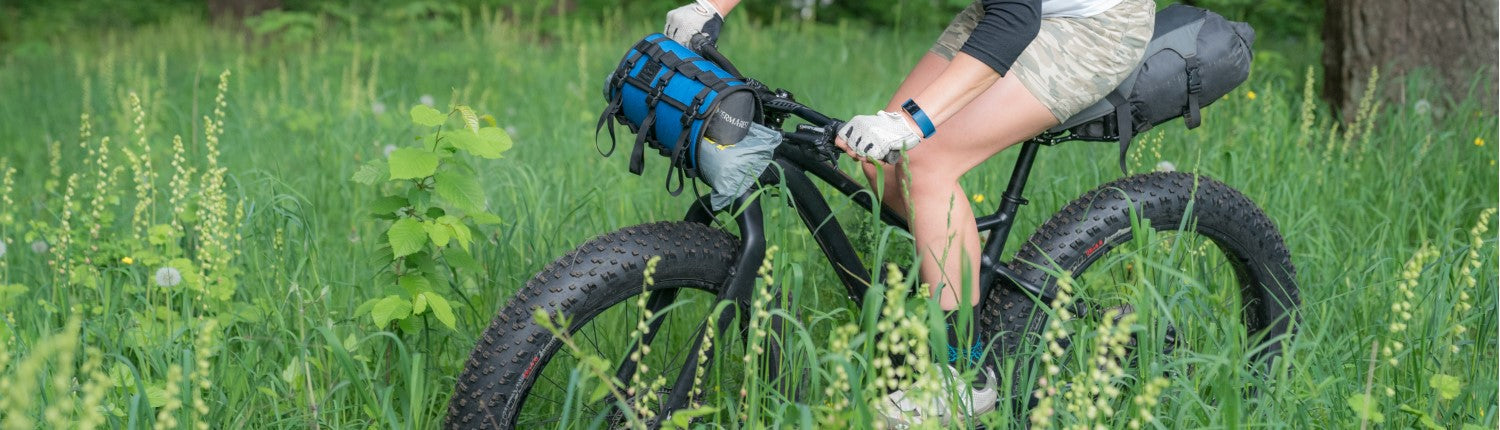 A person riding a fat tire bike through a grassy field with PDW bike accessories.