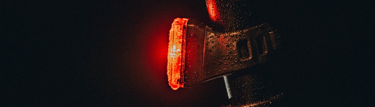 A PDW bike tail light mounted to a bike, lit up at night.