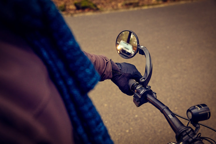 Watch Your Back XL bicycle mirror on a handlebar with a vehicle visible in the mirror.
