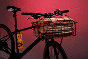A GIF of the red PDW Cargo Web, hooked to a bike basket, illuminating when a light shines on it.